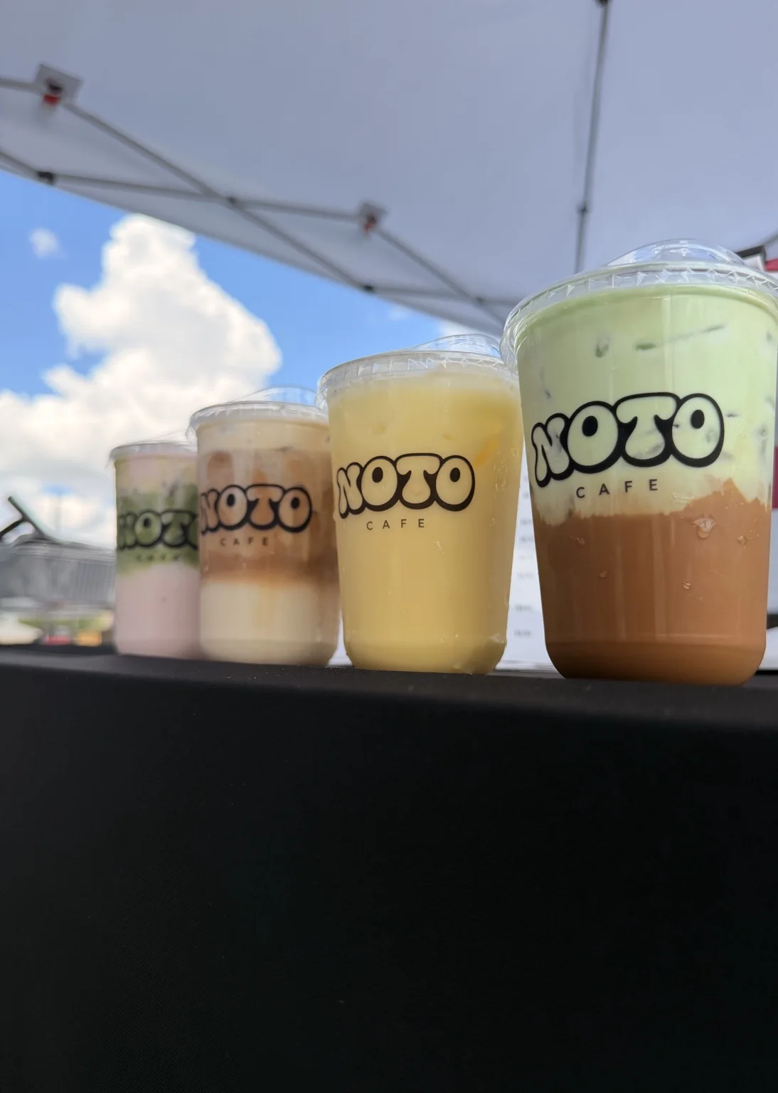 Four colorful branded NOTO drinks at a pop-up